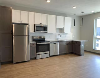 Kitchen with brown lower cabinets, white upper cabinets and bar seating at Haven at Uptown.