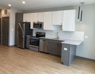 Kitchen with brown lower cabinets, white upper cabinets and bar seating at Haven at Uptown