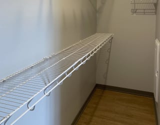Large empty walk in closet with upper and lower wire racks for clothing storage