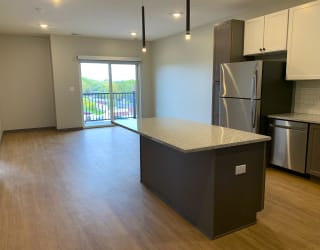Open kitchen to dining room with large granite countertop island at Haven at Uptown in Lincoln, Nebraska