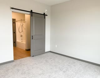 Sliding barn door leading to bathroom in master bedroom at Haven at Uptown in Lincoln, Nebraska