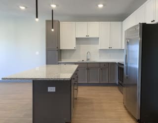 Kitchen with white upper cabinets and gray lower cabinets at Haven at Uptown