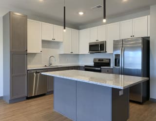 Kitchen with white upper cabinets and gray lower cabinets at Haven at Uptown