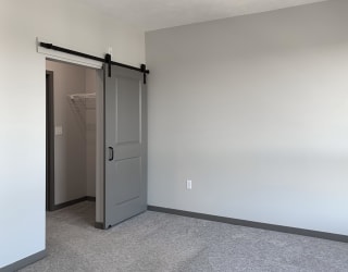 Master bedroom with barn doors leading to closet and bathroom at Haven at Uptown