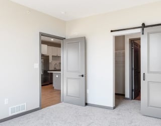 Sliding barn doors leading to closet space and the bathroom from the bedroom in the Bliss floor plan at Haven at Uptown in Lincoln, NE