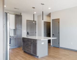 Pendant lighting and island providing seating in the Bliss floor plan kitchen at Haven at Uptown in Lincoln, NE