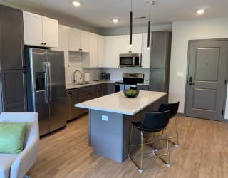 Furnished kitchen in the Slate finish with two tone cabinets, hard wood style flooring, and granite counter tops in the Bliss floor plan at Haven at Uptown