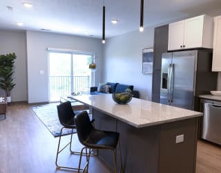 Furnished kitchen in the Slate finish with two tone cabinets, hard wood style flooring, and granite counter tops in the Bliss floor plan at Haven at Uptown