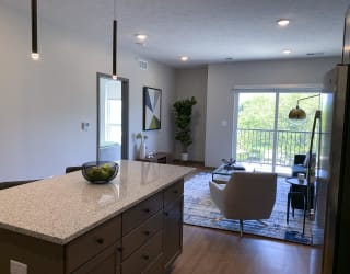 Large kitchen island and furnished living room looking out onto scenic view in Bliss floor plan at Haven at Uptown.