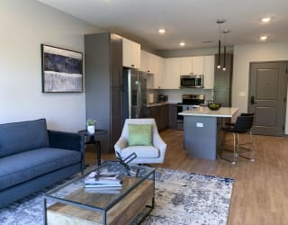 Furnished open concept living room looking into large kitchen in Bliss floor plan at Haven at Uptown in Lincoln.