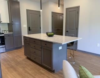 Large kitchen island with abundant storage and bar stools and pendant lights in the Bliss floor plan at Haven at Uptown in Lincoln.