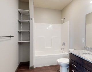 Bathroom with dual sink counter tops, a bathtub, and shelves for additional storage at Haven at Uptown in Lincoln, NE