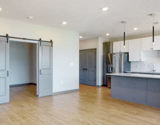 View of sliding barn doors leading into the office area from the living-dining space in the Melody floor plan at Haven at Uptown in Lincoln, NE