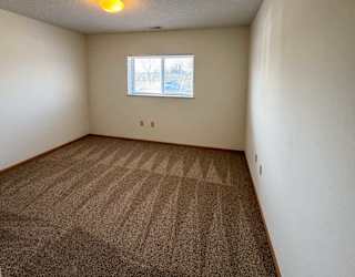 A bedroom with a carpeted floor and a window.