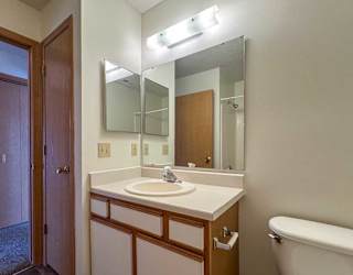 A bathroom with a vanity sink, mirror, medicine cabinet, and overhead lighting.