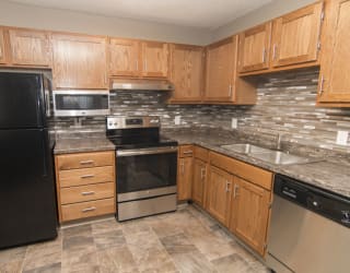 a kitchen with wooden cabinets and a black refrigerator