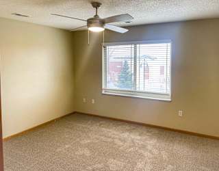 a bedroom with a ceiling fan and a window with blinds