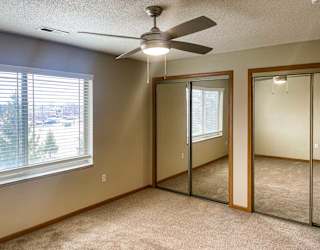 a bedroom with a ceiling fan and two closets with sliding mirrored doors
