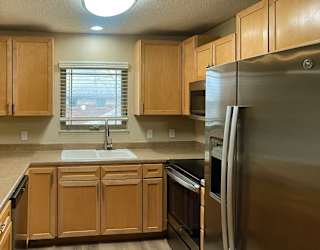 a kitchen with wooden cabinets, stainless steel appliances, and a window above the sink