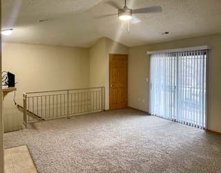 a spacious living room with a ceiling fan, a coat closet, and a sliding glass door to a balcony