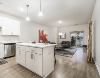 Contemporary design scheme with white kitchen cabinetry, quartz countertops and open layout at The Conrad