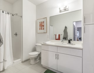 Contemporary bathroom with white cabinetry and white quartz countertops at The Conrad