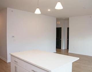 A white kitchen island with a countertop and cabinets in a room with a black door.