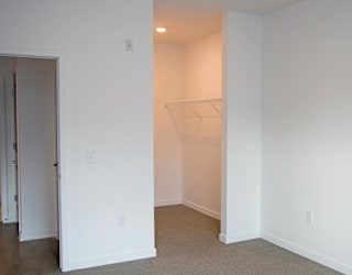 A white room with a doorway leading to another an empty walk-in closet