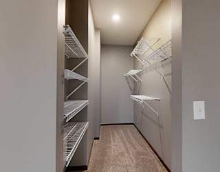 a long, narrow walk-in closet with shelving and a carpeted floor