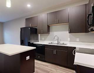 a kitchen with dark brown cabinets and a white granite island