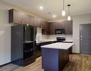 a kitchen with dark cabinets, black appliances, and granite countertops