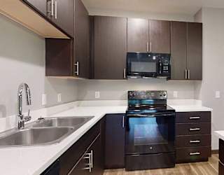 a kitchen with a black oven and microwave, and dark brown cabinets
