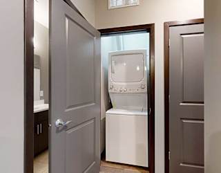 a  laundry room in the hallway with a fullsize stackable washer and dryer