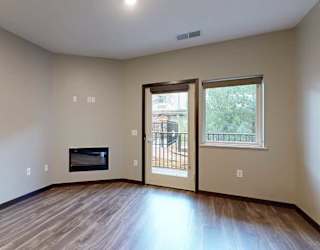 a living room with a fireplace, and a glass door and window looking out to the patio