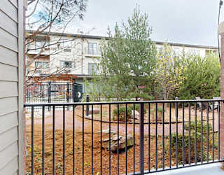 an elevated patio with a metal railing overlooking a courtyard