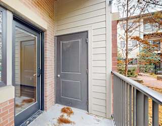 a patio with a door to an outdoor storage closet and a glass door and a window looking from the living room