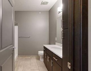 a bathroom with a granite vanity sink and a walk-in shower
