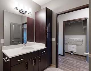 a bathroom with a white granite countertop and dark brown cabinets