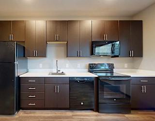 a kitchen with dark brown cabinets, white granite countertops, and black appliances