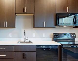 a kitchen with dark brown cabinets and black appliances