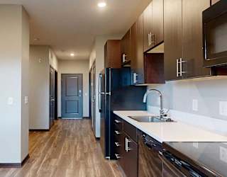 a hallway that connects the entrance to the bathroom, the sleeping area, the kitchen, and the living area