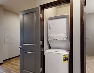 a laundry closet with a stackable full sized washer and dryer