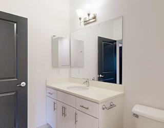 an attached bathroom with a granite vanity sink, a large mirror, and a medicine cabinet