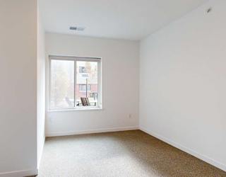 a bedroom with a large window looking out to the courtyard and carpet flooring
