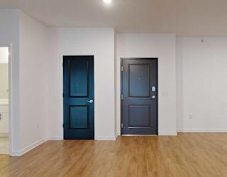 the front door to the 2-bedroom Metz floorplan in a living room with hardwood flooring