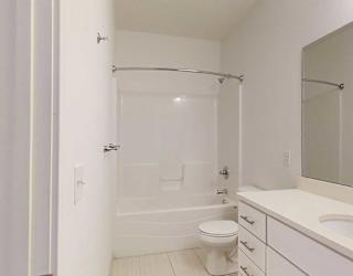 a bathroom with a granite vanity sink and a combination shower and tub