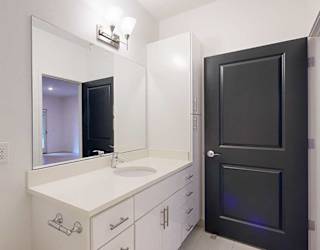 a bathroom with a white granite vanity sink and a tall white storage cabinet