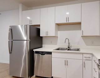 a kitchen with white cabinets and a stainless steel refrigerator next to a stainless steel sink