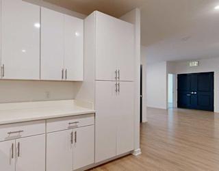 a kitchen with white cabinets and a dining area in the background