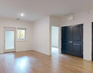 a living room with balcony access and doors to a bedroom and the laundry room